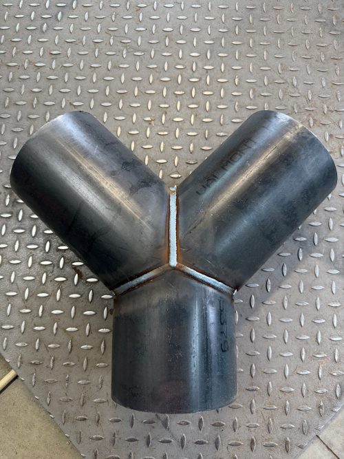 BSWYE08Y | IrrigationSupplyParts.com -- Irrigation Fittings, Camlock, Ringlock, Drip Irrigation, Valves, Gauges Black welded steel pipe elbow joint forming a Y-shape on a diamond-plate metal floor, with blue sealant around the weld.